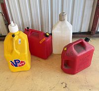 Group of four fuel jugs in assorted colors and sizes