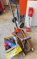 Assorted tools including floor jack, boxed flashlight set, T-handle hex keys, hitch mount, fluid extractor, clamp