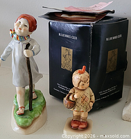 Both figurines beside M.I. Hummel Club box