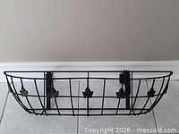 front view of black metal basket window planter with leaf accents and wall brackets