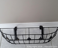 Front view of black metal window planter showing wire construction and leaf accents