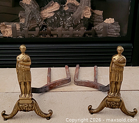 Pair of brass figural andirons in front of fireplace