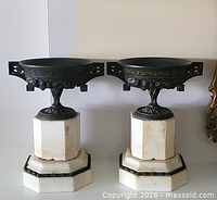 Pair of cast metal urns on marble bases front view