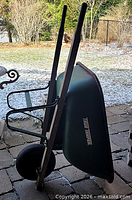Full side view of wheelbarrow upright showing tray, handles and tire