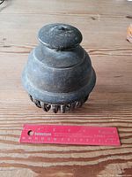 Top and side view of bronze elephant bell beside 6-inch ruler for scale