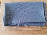 Folded piece of blue-grey wool fabric on wooden surface