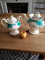 Teapot and sugar bowl side by side on table with apple for scale