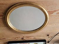 Full view of oval gilt mirror on wall