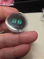 Pair of rectangular emeralds in display case, showing size and matching cut