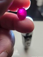 Ruby held between fingers, front facet visible