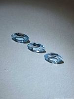 Three marquise-cut light blue gemstones on neutral background
