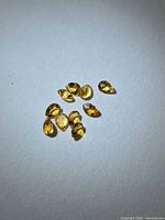 Group of nine pear-cut golden citrine stones on white background
