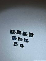 Nine square princess cut sapphires laid out on white surface