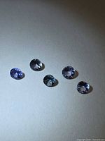 Five round tanzanites on neutral background