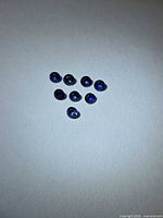 Eight round blue sapphires arranged in a triangle on white background