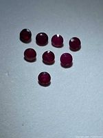 Eight round red rubies arranged on light background
