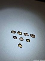 Eight faceted gemstones on white background under spotlight