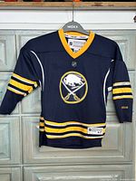 Front view of Buffalo Sabres youth Reebok jersey on hanger