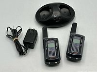 Two handheld radios, charging base, AC adapter laid out