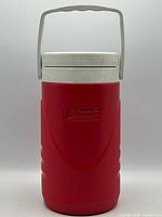 Front view of red Coleman water jug showing logo, handle and body condition