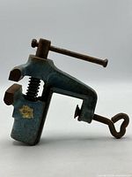 Left side view of blue cast iron clamp-on vise showing jaws, spring, decal, and clamp screw