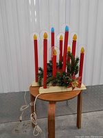 Front view showing both cream bases, red candle tubes, flame bulbs, greenery and cords
