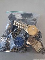 Bag showing multiple watches including blue dial Seiko, gold-tone day/date, square gold watch