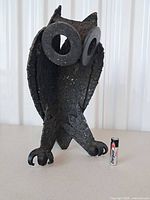 Front view of cast-iron owl sculpture with battery for scale