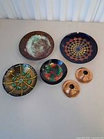 Top view showing five enamel on copper dishes and two copper candlesticks