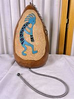Full view of gourd rainmaker showing Kokopelli design, chain, and pull cord