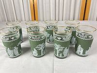 Group view of all eight green tumblers showing classical motifs and gold rims