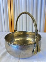 front view of brass bowl showing handle and hammered texture