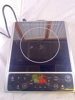 Top view showing black glass surface, circular cooking zone, controls and display