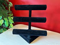 Full view of three-tier black velvet jewelry display stand on table