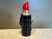 Full view of closed lipstick-shaped case standing upright