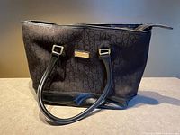 Full view of Calvin Klein monogram tote showing exterior, handles and base