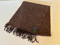 Full view of scarf folded showing texture and fringe with brand tag visible