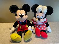 Front view of both plush dolls seated upright