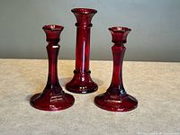 Three ruby red glass candlesticks front view
