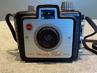 Front view of Kodak Brownie Holiday Flash camera showing lens, logo, body styling, wrist strap
