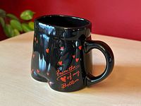 Side view of black boxer shorts mug with handle and red heart pattern