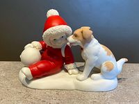 Front view of Snowbabies figurine showing Snowbaby in red suit with dog and snowball