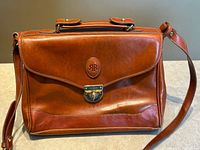 Front view showing overall shape, leather finish, top handle, shoulder strap
