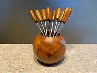 Set of cocktail picks displayed in spherical olive wood holder