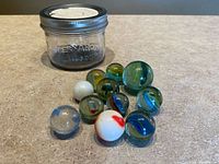 Group of assorted marbles arranged in front of Bernardin Mason jar with lid