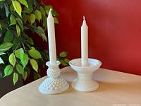 Both milk glass candlesticks with candles for scale