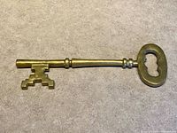 Full view of entire oversized brass skeleton key on flat surface