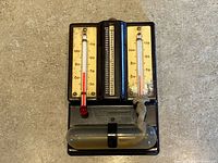 Front view showing two thermometers, rotating humidity scale, glass reservoir