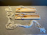 Two wooden hanging shelves with rope and a macramé plant hanger laid on countertop