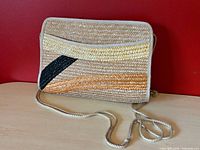 Front view of woven straw crossbody bag showing color-block design, slip pocket and strap